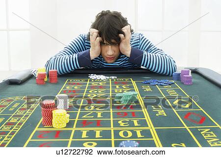 Stock Image - Young frustrated man at roulette table. Fotosearch