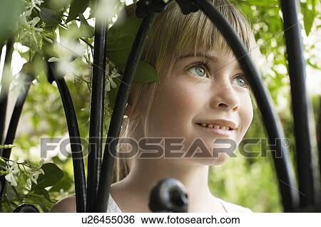 Stock Photograph - Young girl among branches, smiling, portrait, close-up. Fotosearch