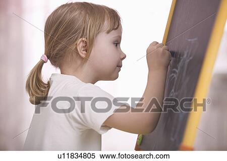 Stock Photography - Young girl drawing on chalkboard. Fotosearch
