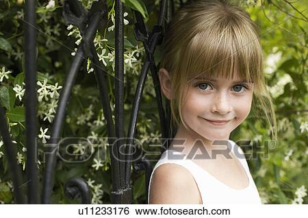 Young girl leaning on fence, smiling, portrait View Large Photo Image Stock Photograph - Young girl leaning on fence, smiling, portrait. Fotosearch