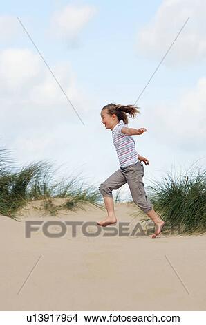 Picture - Young girl running on beach, side view. Fotosearch