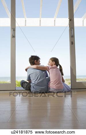 Young girl with arm around young boy sitting on floor in doorway View Large Photo Image Stock Photography - Young girl with arm around young boy sitting on floor in doorway. Fotosearch
