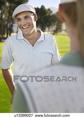 Young golfers on course, focus on smiling man View Large Photo Image Stock Photo - Young golfers on course, focus on smiling man. Fotosearch