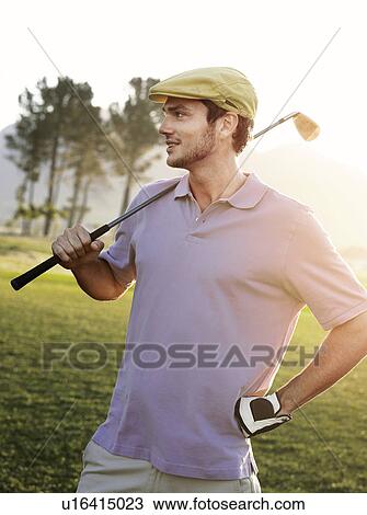 Young male golfer standing on course, holding club on shoulder View Large Photo Image Stock Image - Young male golfer standing on course, holding club on shoulder. Fotosearch
