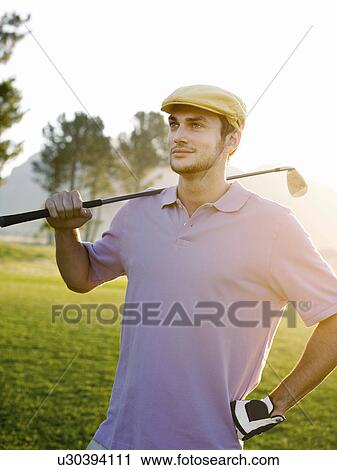 Young male golfer standing on course, holding club on shoulder, portrait View Large Photo Image Stock Image - Young male golfer standing on course, holding club on shoulder, portrait. Fotosearch