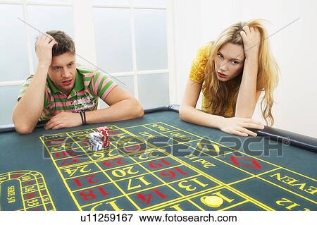 Stock Photo - Young man and woman losing on roulette table. Fotosearch
