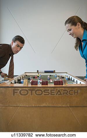 Young man and woman playing table football in games room View Large Photo Image Stock Image - Young man and woman playing table football in games room. Fotosearch