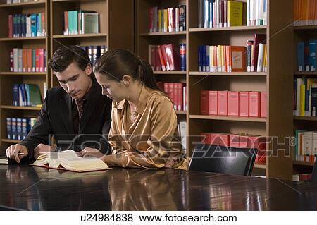Stock Photo - Young man and woman studying at desk in library. Fotosearch