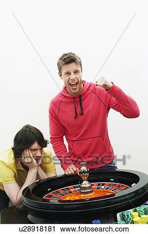 Young man celebrating at roulette wheel while friend loses, portrait View Large Photo Image Stock Image - Young man celebrating at roulette wheel while friend loses, portrait. Fotosearch