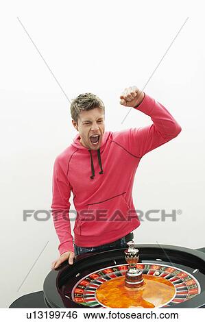 Stock Photograph - Young Man celebrating at roulette wheel. Fotosearch
