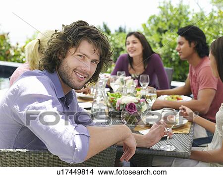 Picture - Young man enjoying outdoor dinner party smiling to camera. Fotosearch