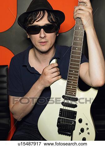 Young man in sunglasses holding guitar, portrait View Large Photo Image Stock Photo - Young man in sunglasses holding guitar, portrait. Fotosearch