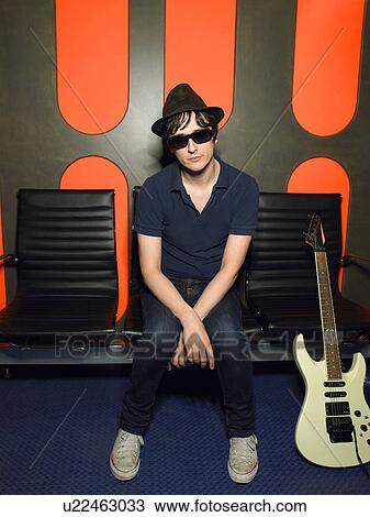 Stock Image - Young man in sunglasses with guitar, portrait. Fotosearch