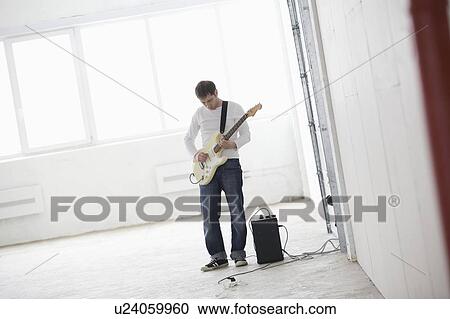 Young man playing electric guitar View Large Photo Image Stock Image - Young man playing electric guitar. Fotosearch