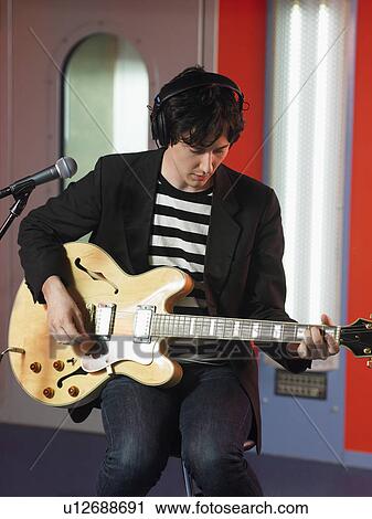 Young man playing guitar in recording studio, portrait View Large Photo Image Stock Image - Young man playing guitar in recording studio, portrait. Fotosearch
