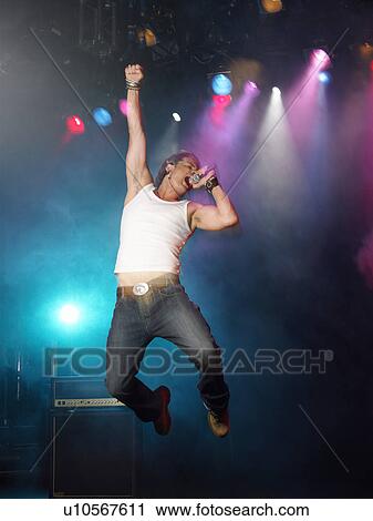 Young Man Singing and jumping on stage at concert, low angle view View Large Photo Image Stock Image - Young Man Singing and jumping on stage at concert, low angle view. Fotosearch
