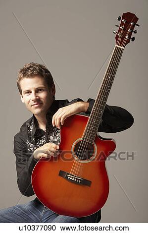 Young Man sitting with Acoustic Guitar, smiling, portrait View Large Photo Image Stock Image - Young Man sitting with Acoustic Guitar, smiling, portrait. Fotosearch