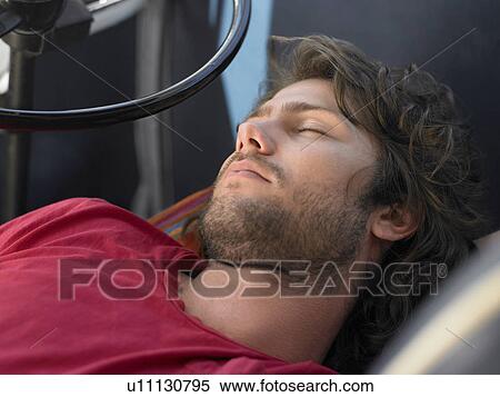 Stock Photography - Young Man Sleeping in Vehicle, head and shoulders. Fotosearch