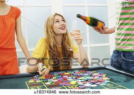 Stock Photograph - Young woman celebrating with friends at roulette table. Fotosearch