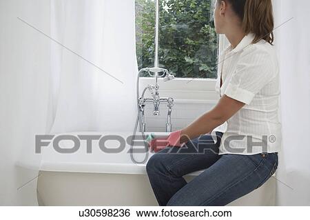 Stock Photograph - Young woman cleaning bathroom. Fotosearch