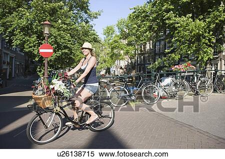 Young woman cycles bike with cut flowers in basket, Amsterdam View Large Photo Image Stock Photography - Young woman cycles bike with cut flowers in basket, Amsterdam. Fotosearch