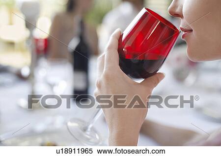 Stock Photography - Young woman drinking from wineglass, close-up, side view. Fotosearch