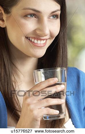 Stock Photo - Young woman drinking glass of water, portrait. Fotosearch