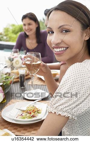 Stock Image - Young Woman Drinking Wine outdoors at a dinner party. Fotosearch