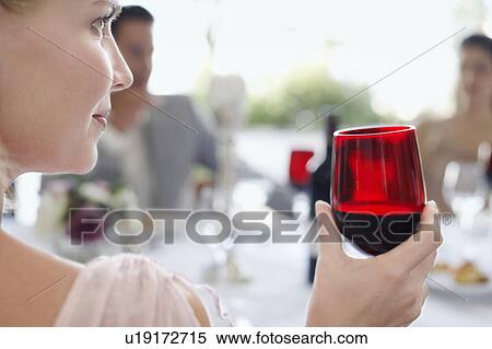 Stock Photography - Young woman holding wineglass, close-up, back view. Fotosearch