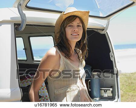 Stock Photography - Young woman leaning on open tailgate of van, half length. Fotosearch