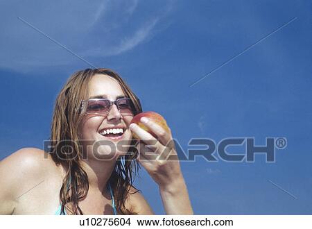 Young Woman Looking at Apple, smiling View Large Photo Image Picture - Young Woman Looking at Apple, smiling. Fotosearch