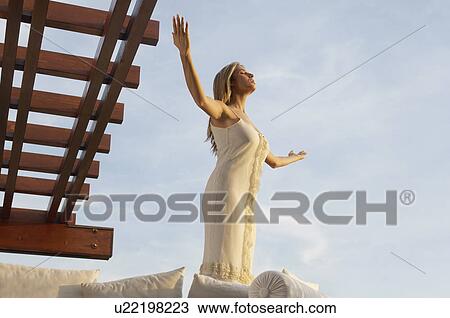 Stock Image - Young woman practising yoga, portrait, low angle view. Fotosearch