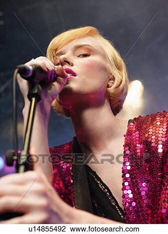 Stock Image - Young Woman Singing in Concert on stage, low angle view, close up. Fotosearch