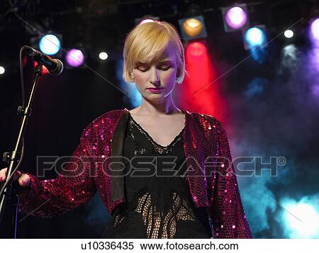 Stock Photography - Young Woman Singing in Concert on stage, front view, low angle view. Fotosearch