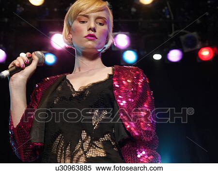 Stock Photography - Young Woman Singing in Concert on stage, front view, low angle view. Fotosearch