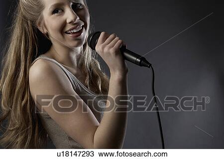 Stock Image - Young woman singing in studio, close-up. Fotosearch