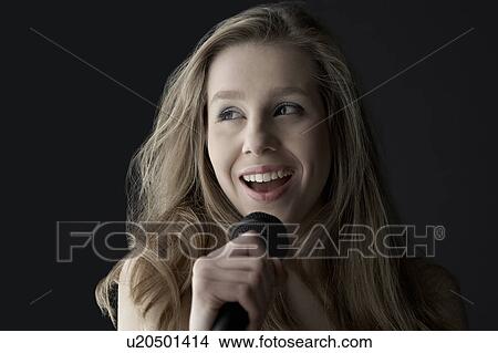 Young woman singing into microphone, close-up View Large Photo Image Picture - Young woman singing into microphone, close-up. Fotosearch