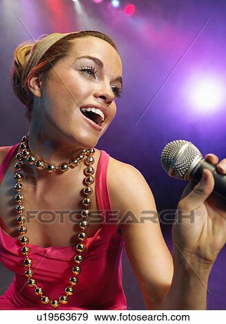 Stock Photo - Young Woman Singing on stage in Concert, close up, low angle view. Fotosearch