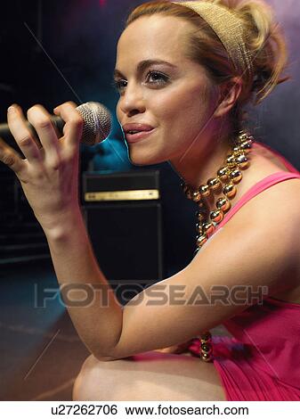 Stock Photograph - Young Woman Singing on stage in Concert, close up, side view. Fotosearch