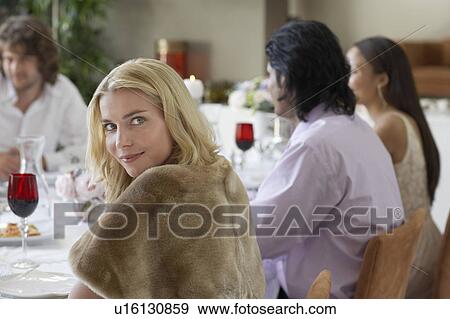Stock Photo - Young woman sitting at table of formal dinner party. Fotosearch