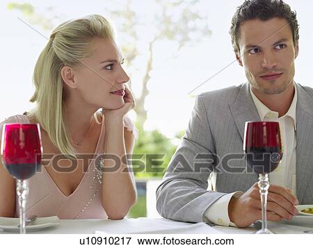 Stock Photo - Young Woman sitting, hand on chin, Adoring Man sitting beside her. Fotosearch