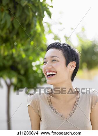 Young woman sitting in plaza laughing View Large Photo Image Picture - Young woman sitting in plaza laughing. Fotosearch