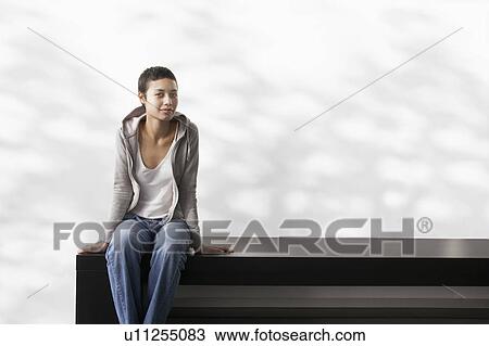Young woman sitting indoors on bench, portrait View Large Photo Image Stock Image - Young woman sitting indoors on bench, portrait. Fotosearch