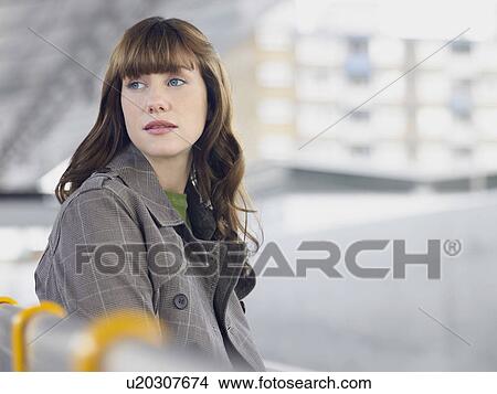 Picture - Young woman sitting, looking back over shoulder. Fotosearch