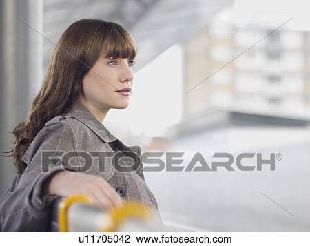 Young woman sitting on bench, looking away, side view View Large Photo Image Stock Image - Young woman sitting on bench, looking away, side view. Fotosearch