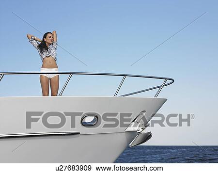 Stock Photo - Young woman standing in bow of yacht. Fotosearch