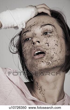 Stock Image - Young woman with bandage and muddy face. Fotosearch