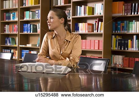 Young woman with book, working at desk in library View Large Photo Image Stock Photo - Young woman with book, working at desk in library. Fotosearch