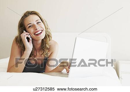 Happy woman on phone, lying on bed View Large Photo Image Stock Photography - Happy woman on phone, lying on bed. Fotosearch