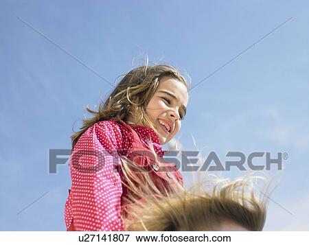 Low angle view of young girl (5-7) on mother's shoulders in wind (only mother's hair visible), Alicante, Spain, View Large Photo Image Stock Photo - Low angle view of young girl (5-7) on mother's shoulders in wind (only mother's hair visible), Alicante, Spain,. Fotosearch